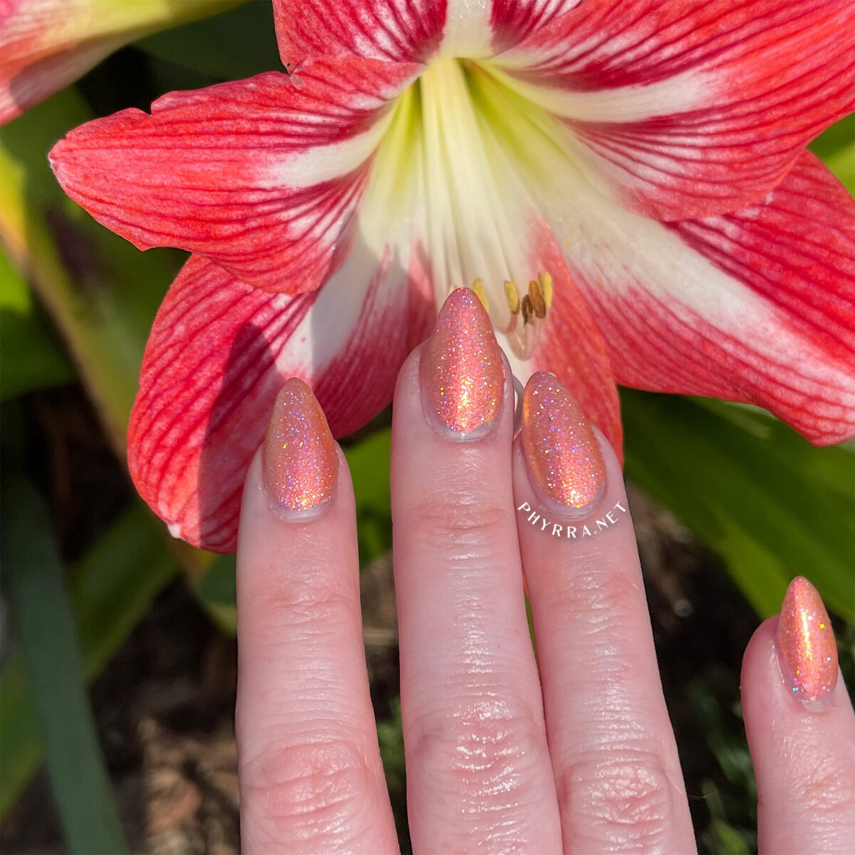 Cupcake Polish Shimmering Sunburst Mani in front of a blooming flower