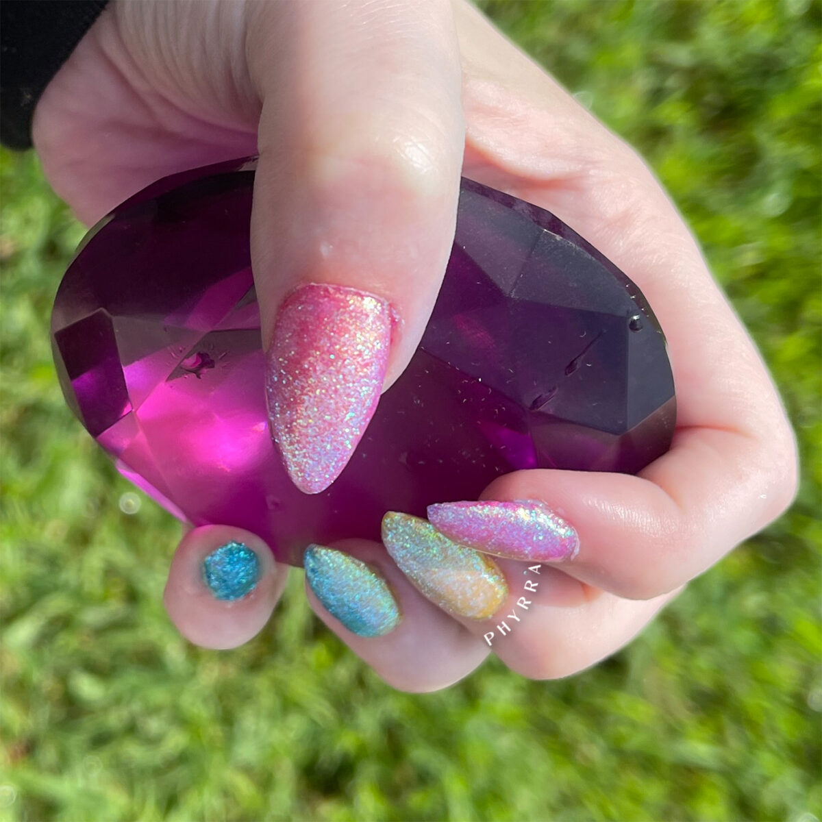 Cordelia holding a purple gem with pan pride nails