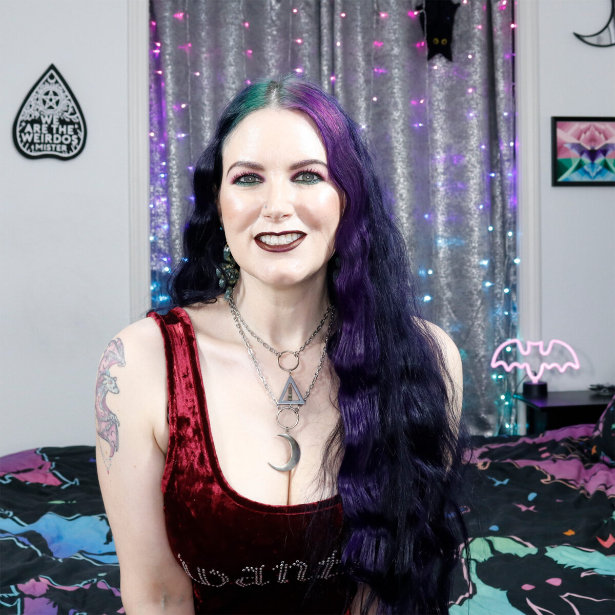 Cordelia is wearing a burgundy crushed velvet crop top that says Wanted