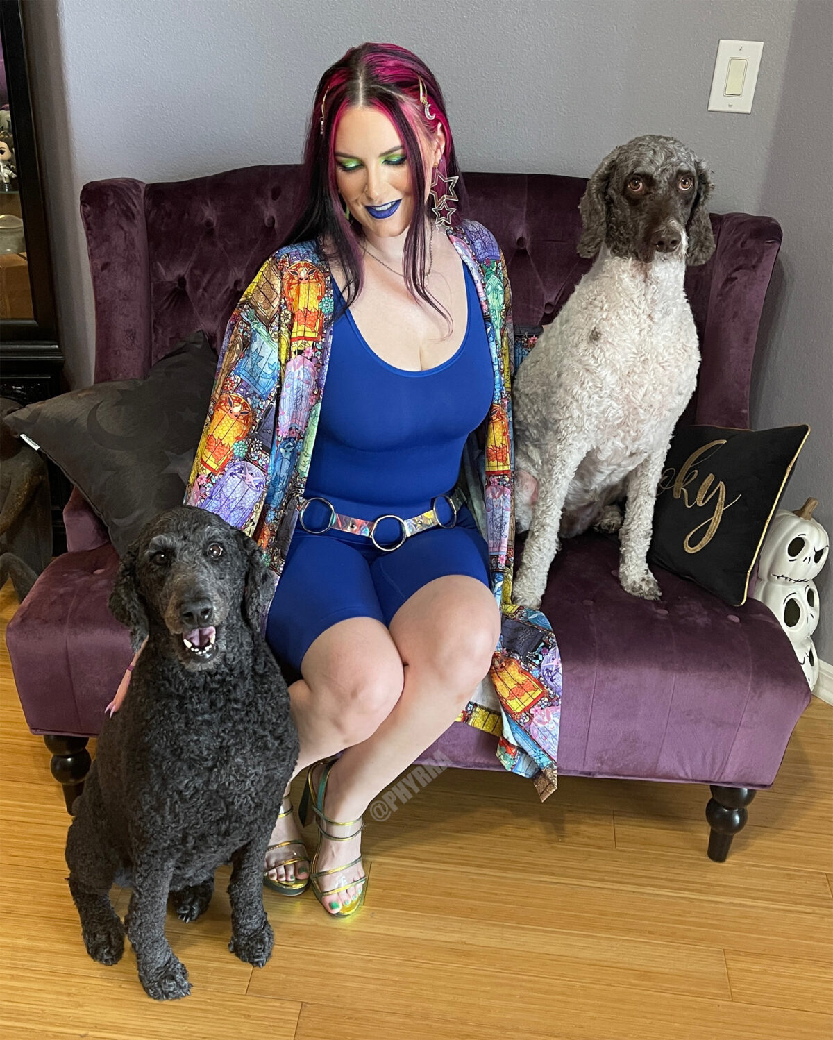 Cordelia is wearing a tank bodysuit and sitting with her two standard poodles